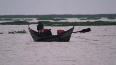 Tahta kanodaki dört adam göle su salıyor.