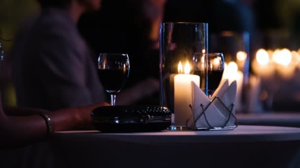 Imágenes de cerca de la mesa elegantemente decorada en el restaurante, visitante femenina sosteniendo una copa de vino tinto, bolso de embrague negro de lujo está cerca . — Vídeos de Stock