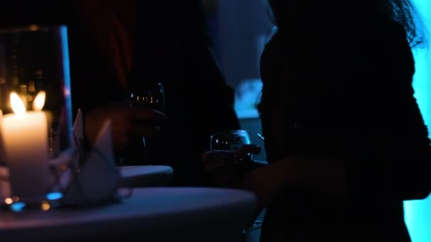 Images de deux personnes dans une ombre tenant des verres à vin près de la table à la boîte de nuit . — Video