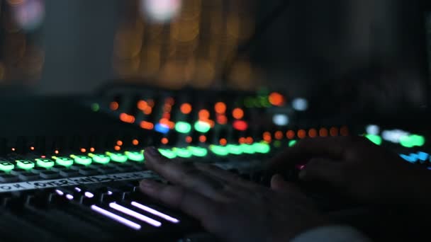 Imagen de cerca de manos masculinas colocadas en un escritorio de control de sonido. Ingeniero de audio opera su instrumento, equipo de grabación, durante un espectáculo nocturno en la sala de conciertos . — Vídeo de stock