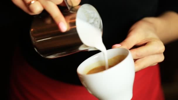 Manos de barista haciendo café con leche o capuchino vertiendo leche haciendo arte de café con leche . — Vídeo de stock