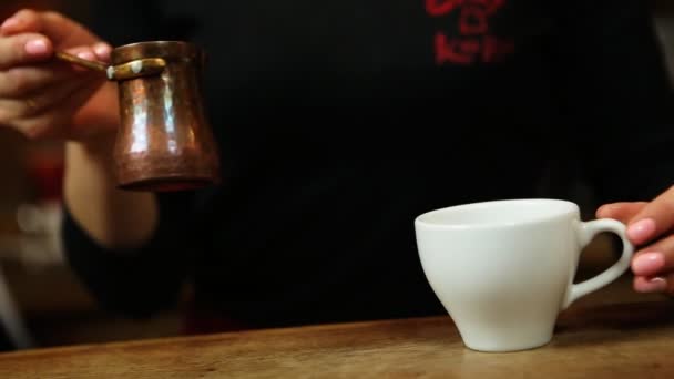 Café brassé est versé à partir d'un café turque de cuivre dans une tasse blanche — Video