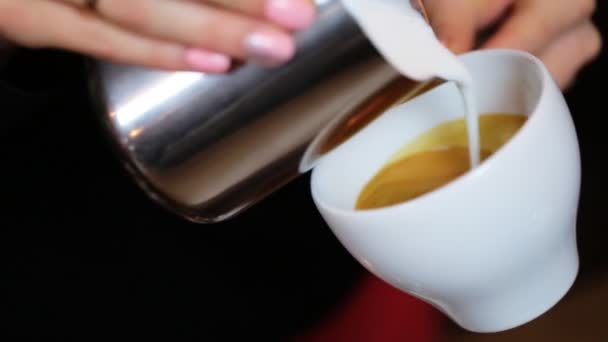 Händerna på barista att göra latte eller cappuccino kaffe häller mjölk att göra latte art. — Stockvideo