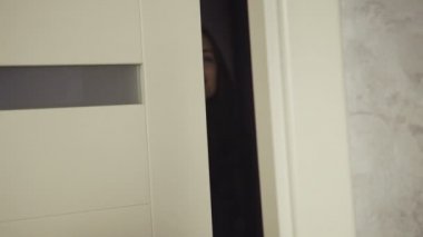 Slow motion footage of handsome cheerful girl opens the door of an apartment, goes out, spins and dances with joy.