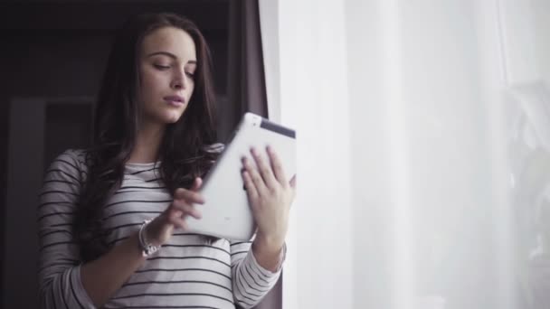 Retrato de uma bela mulher branca na casa dos 20 anos que usa touchpad em uma sala de estar . — Vídeo de Stock