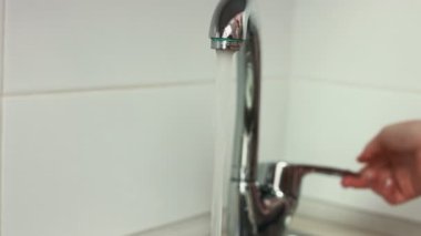 Eller yakın çekim görüntüleri bir musluk açar ve bir mutfak domates yıkar.