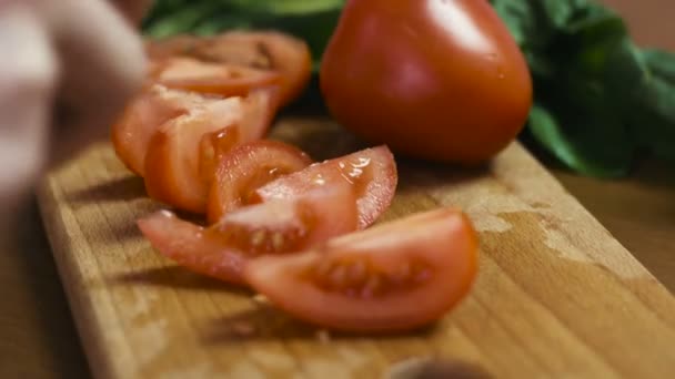 Foto de manos femeninas jóvenes cortando tomate a rodajas grandes en una tabla de madera . — Vídeos de Stock