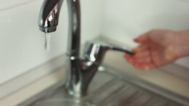 Eller yakın çekim görüntüleri bir musluk açar ve pişirmeden önce domates su ile temizlik.