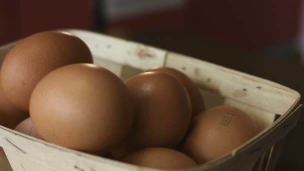 Un primo piano di un cesto di uova marroni giace su una tavola di legno che gira . — Video Stock