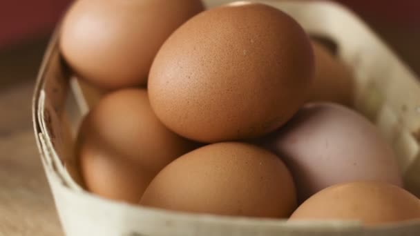 Oeufs bruns dans un panier en bois tournant autour sur une table — Video