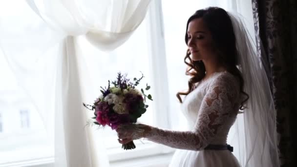 A bride of incredible beauty holding bridal bouquet at her left hand and smelling flowers aroma. — Stock Video