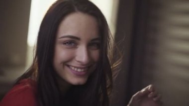 Çekici bir genç uzun saçlı esmer erkek portresi kameraya poz bir kırmızı t-shirt yıpranmış.