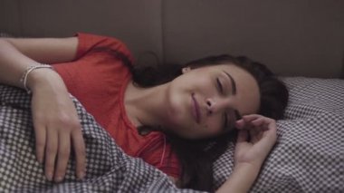 Kendini bir yatakta uyuyor sonra germe yakışıklı bir kız ağır çekim görüntüleri.