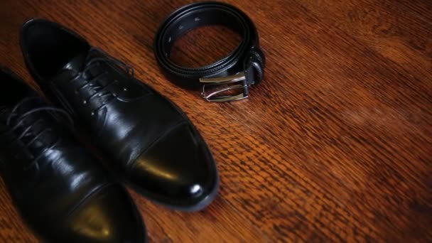 Gros plan de ceinture en cuir et chaussures élégantes noires isolées sur un fond en bois . — Video