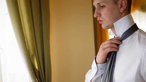 Succesvolle man dragen witte shirt fix zijn das op de kamer — Stockvideo