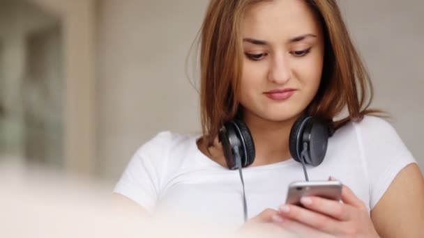 Gelukkig aantrekkelijke vrouw luisteren muziek met koptelefoon in beweging dansen op witte achtergrond. — Stockvideo