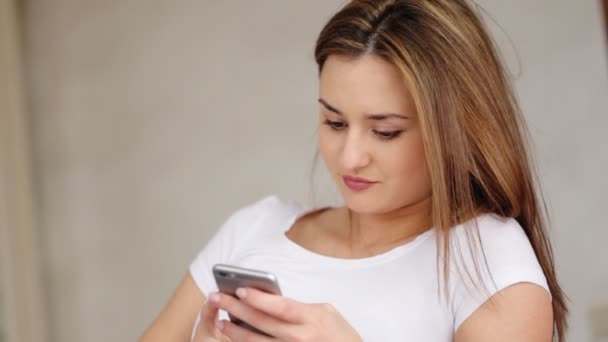 Mujer joven casual charlando por el teléfono celular con sus amigos durante su descanso o vacaciones en casa . — Vídeo de stock