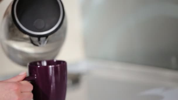 Mujer vertiendo agua en la taza, haciendo un té para sí misma en la cocina contemporánea de lujo . — Vídeos de Stock