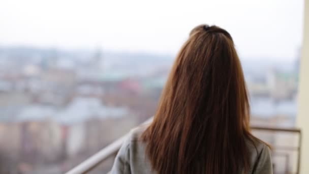 Hermosa mujer sonriente en abrigo gris que permanece en el balcón y posando en la cámara . — Vídeos de Stock