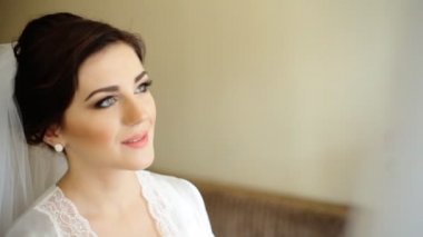 Genç güzel mutlu gelin ona düğün dokunmadan elbise ve Kameraya gülümse.