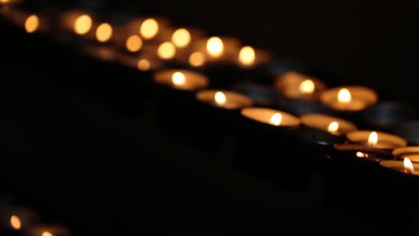 Putten hodně hořící svíčky na řádku v kostele. — Stock video