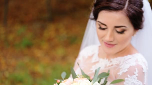 Young cute smiling bride with blue eyes holding a bouquet of flowers in her hands. — Stock Video