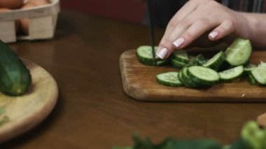 Genç ev hanımı onun kadın evde taze greencucumbers, yumurta ve Filiz salatası yapıyor.