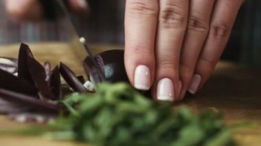 Genç ev hanımı slicingred soğan halkaları bir kesme tahtası üzerinde bıçağını tablewith içine.