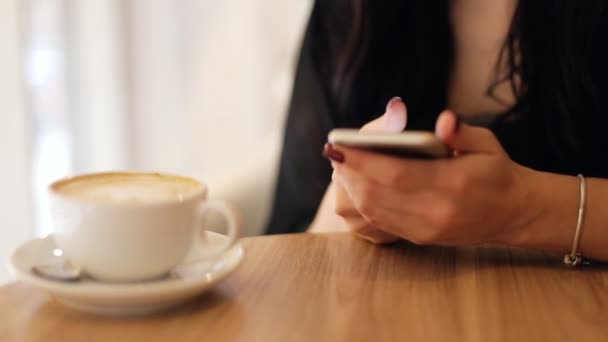 Primer plano de las manos femeninas usando el teléfono móvil en una cafetería  . — Vídeo de stock