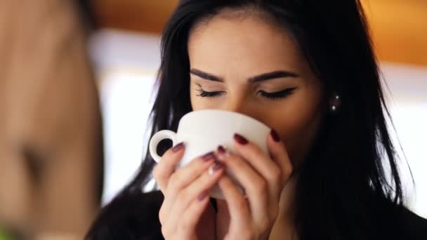 Unglaublich attraktive junge Frau trinkt heißen leckeren Kaffee in einer Cafeteria. — Stockvideo