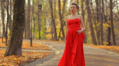 Kadın kırmızı elbise ve güzel kırmızı moda ayakkabı bir prenses gibi park yürüyüş.