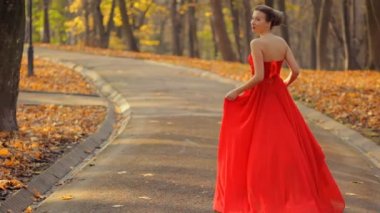 Çekici kadın kırmızı uzun gece elbisesi yeşil yaz parkta yürüyüş.