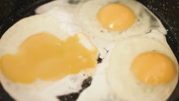 Trois œufs frits préparés sur une poêle en fonte et traités avec un sel .