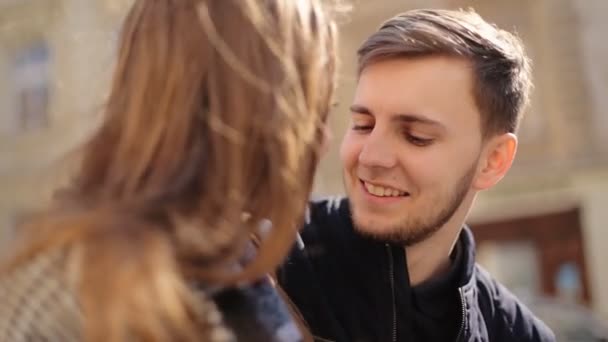 Jonge verlegen man praten met zijn vriendin zittend op het bankje op de straat. — Stockvideo