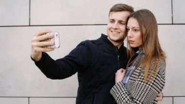 Güzel çekici gülümseyen kadın yakışıklı erkek arkadaşı ile onun telefonunda selfies alarak.