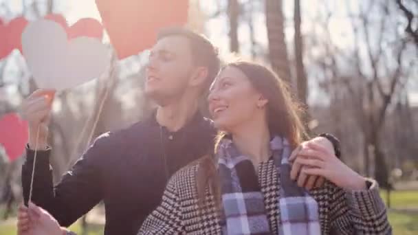 Joven pareja encantadora que tiene tiempo increíble en el hermoso parque con una decoración increíble hecha de corazones blancos y rojos . — Vídeos de Stock