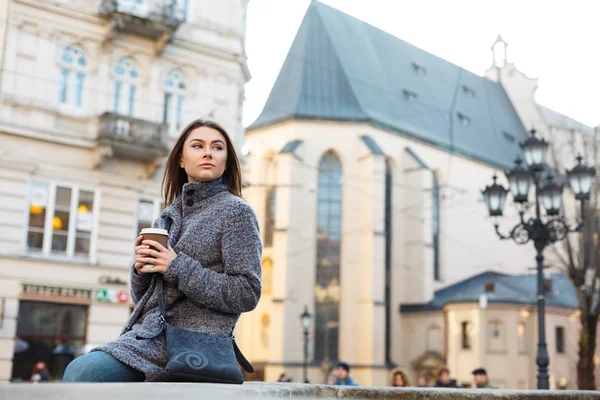 Joven mujer elegante caminando por la calle y sosteniendo una taza de café en sus manos . — Foto de Stock