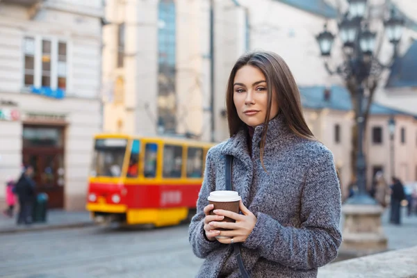 Joven mujer elegante caminando por la calle y sosteniendo una taza de café en sus manos . — Foto de Stock