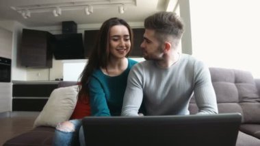 Laptop onun e-postaları denetleme ve kız onu onududaklarından öpüyorsun, konuşmaya delikanlı bir koltukta oturan güzel Çift.