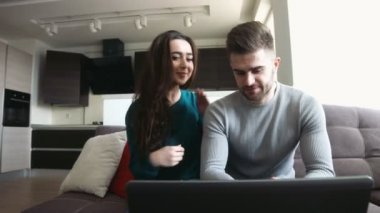 Laptop onun e-postaları denetleme ve kız onu onududaklarından öpüyorsun, konuşmaya delikanlı bir koltukta oturan güzel Çift.