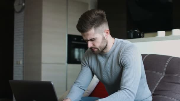 Сексуальний красивий чоловік, використовуючи свій ноутбук, відпочиває у своїй вишуканій квартирі  . — стокове відео