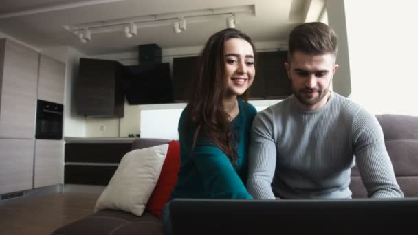 Casal bonito fazendo compras via internet, homem beijando sua namorada, dentro de casa . — Vídeo de Stock