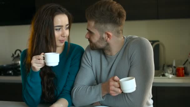 Krásný pár, zůstat v kuchyni, pití kávy a mluvit k sobě navzájem. — Stock video