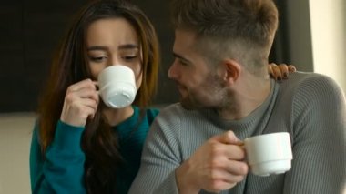 Mutlu genç, çift evde rahatlatıcı gülümseyen içme kahve ve kadın adam evde onunla konuş.