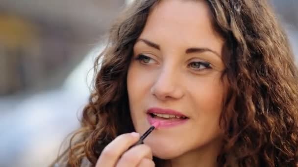 Young pretty lady using her lipstick in the street. — Stock Video