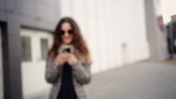 Pretty girl in sunglasses messaging with her friends in the street. — Stock Video