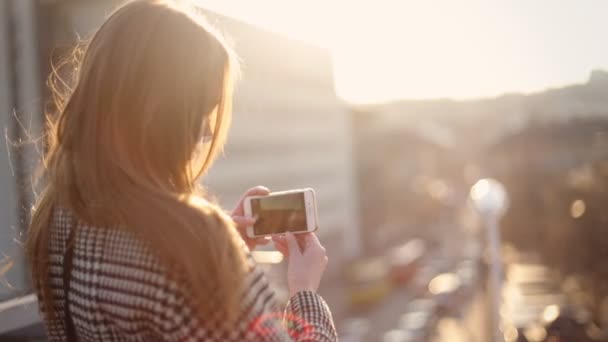 Nahaufnahme einer jungen Frau, die Bilder von einem schönen Stadtpanorama macht. — Stockvideo