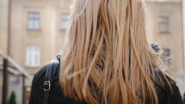 Schöne blonde junge Frau, die auf der Straße geht — Stockvideo