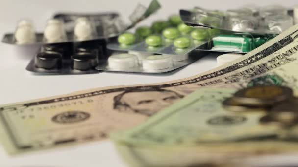 Montón de medicamentos farmacéuticos y píldoras de la medicina dispersos en dinero en efectivo en dólares, el costo del medicamento y el concepto de tratamiento — Vídeos de Stock