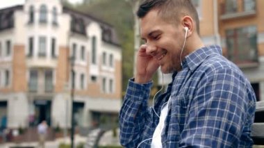 Mutlu adam--dan bir akıllı telefon bir sıcaklık günbatımı şehir arka plan ile müzik